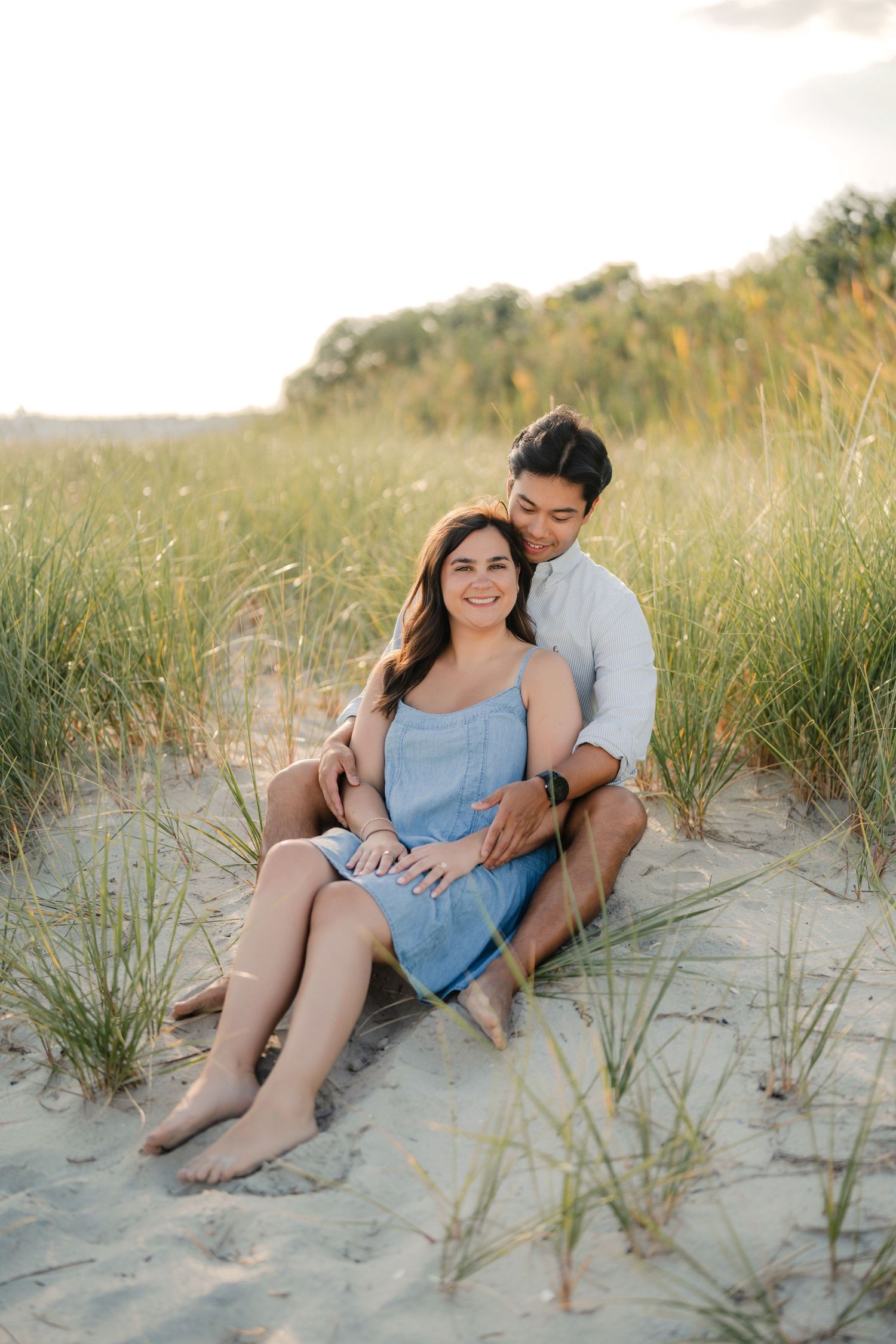 Man proposes on one knee to woman on a wooden boardwalk outside a historic brick building.