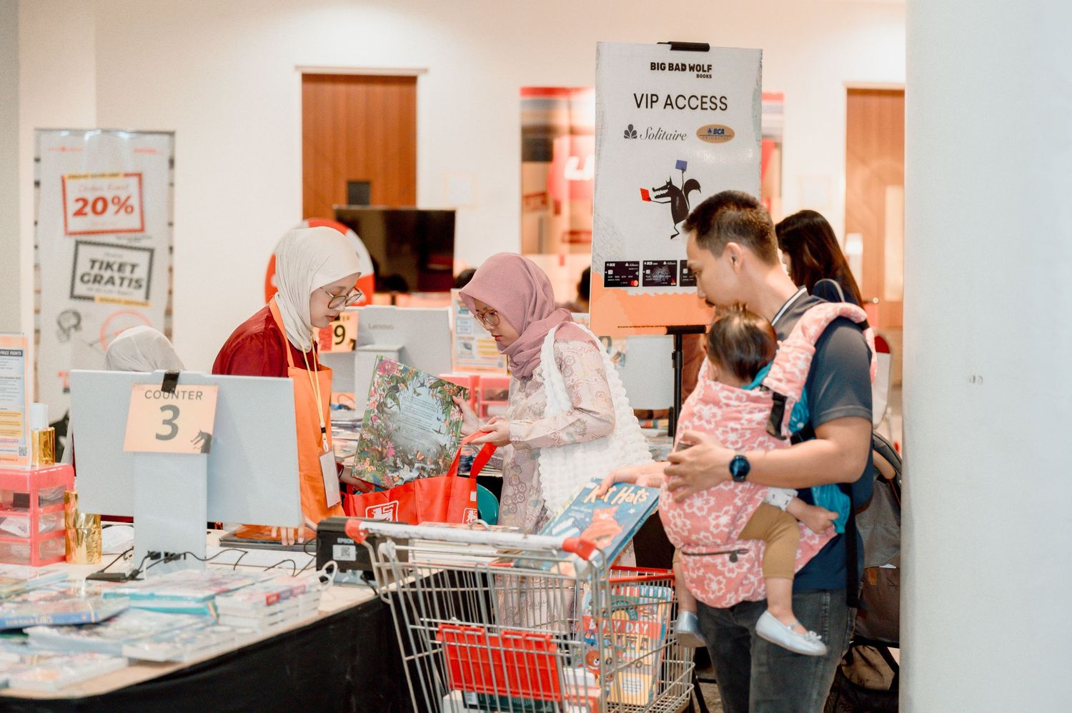Family with baby checking out at a retail store checkout counter with a shopping cart.