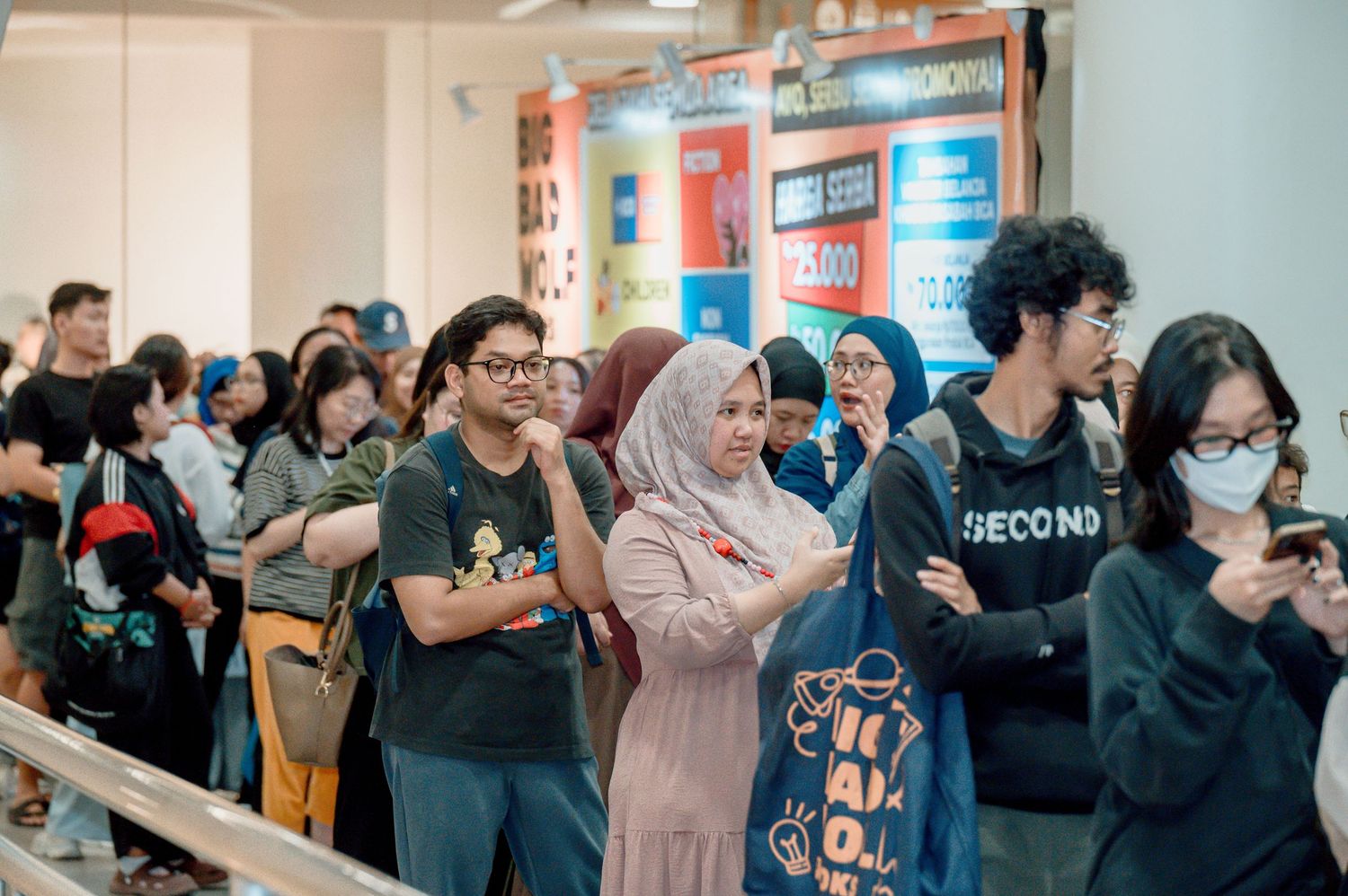 Diverse crowd of young people waiting in line at a busy indoor event or shopping mall in Southeast Asia.
