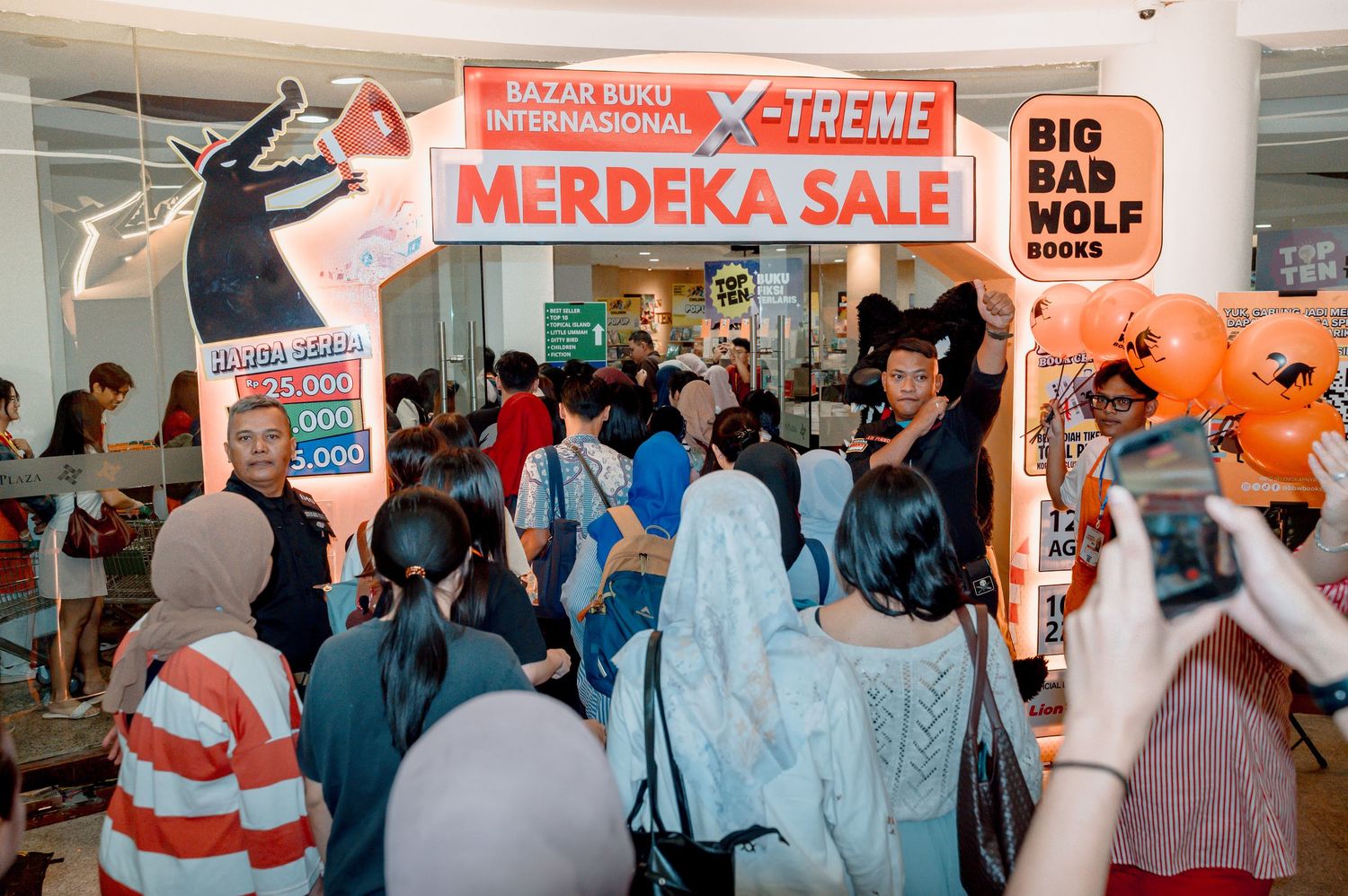 Crowd of shoppers at Big Bad Wolf Books X-Treme Merdeka Sale event with orange promotional banners.