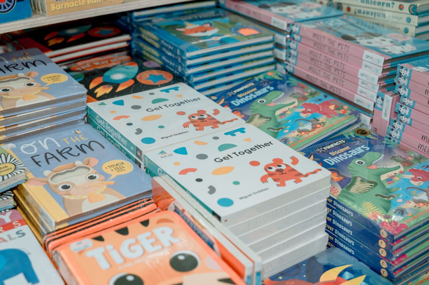 Colorful children's board books stacked on display, including titles like Get Together, Tiger, and On the Farm.