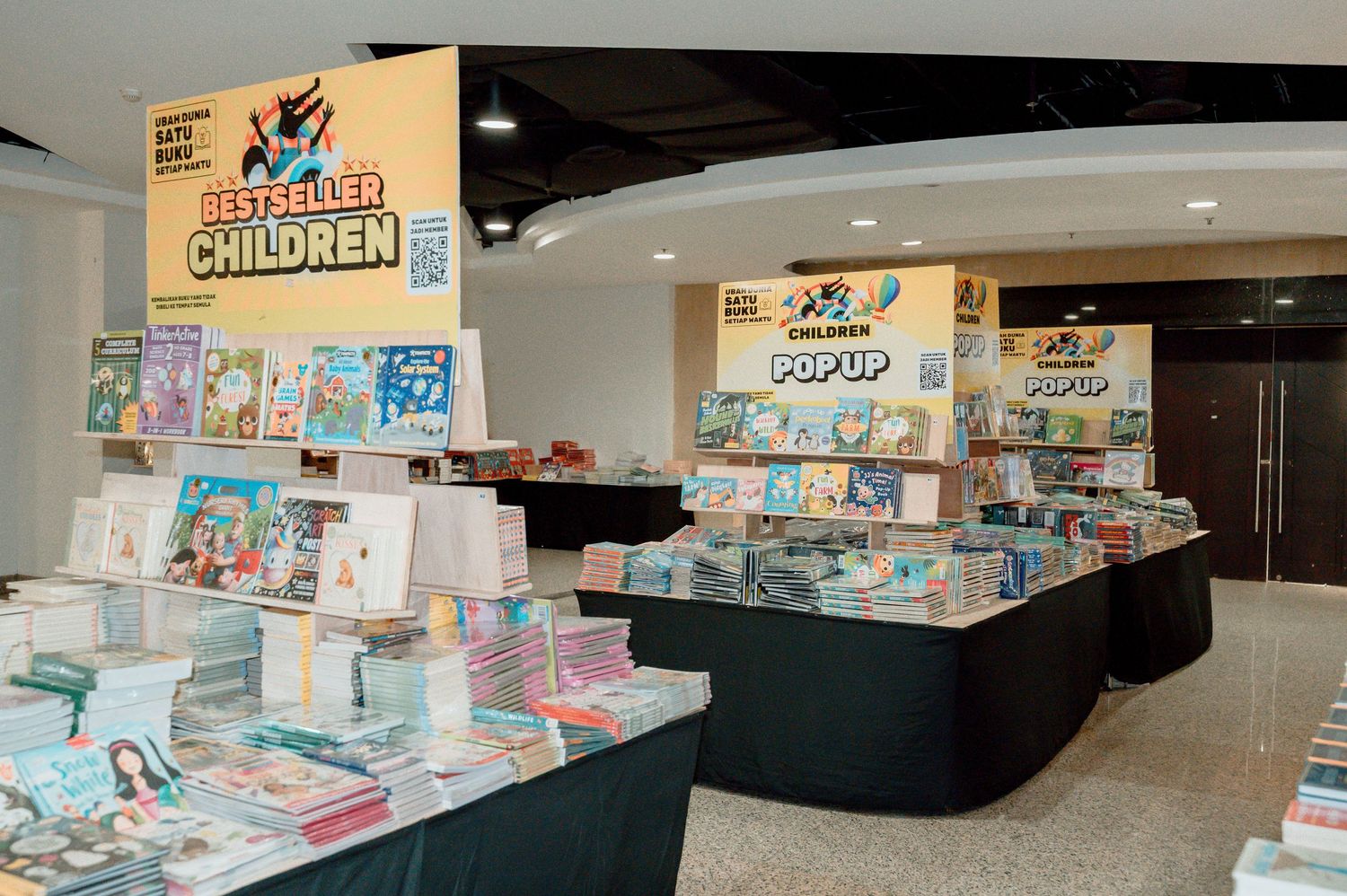 Bestseller children's book display at a pop-up bookstore with colorful titles arranged on black tables.