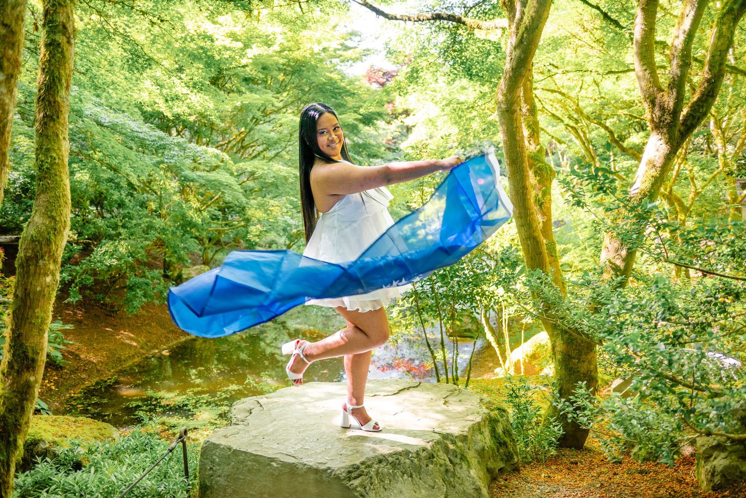 Graduate celebrating with the flag of Chuuk State during her Bellevue Botanical Garden graduation session