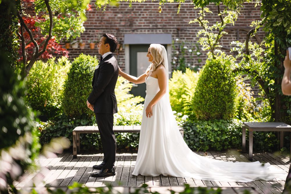 Bride and groom share emotional first look moment in lush garden on wedding day.