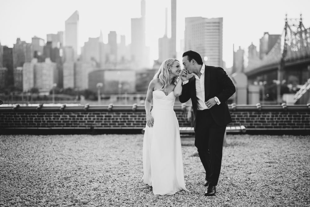 Black and white photo of bride and groom sharing a tender moment with NYC skyline backdrop.