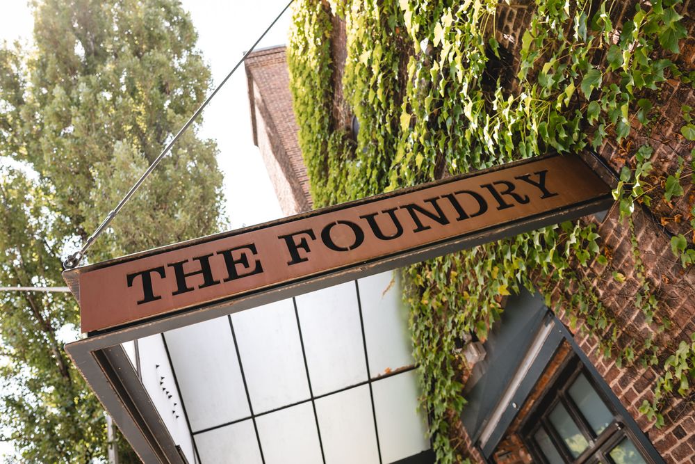 The Foundry restaurant sign mounted on ivy-covered brick wall exterior.