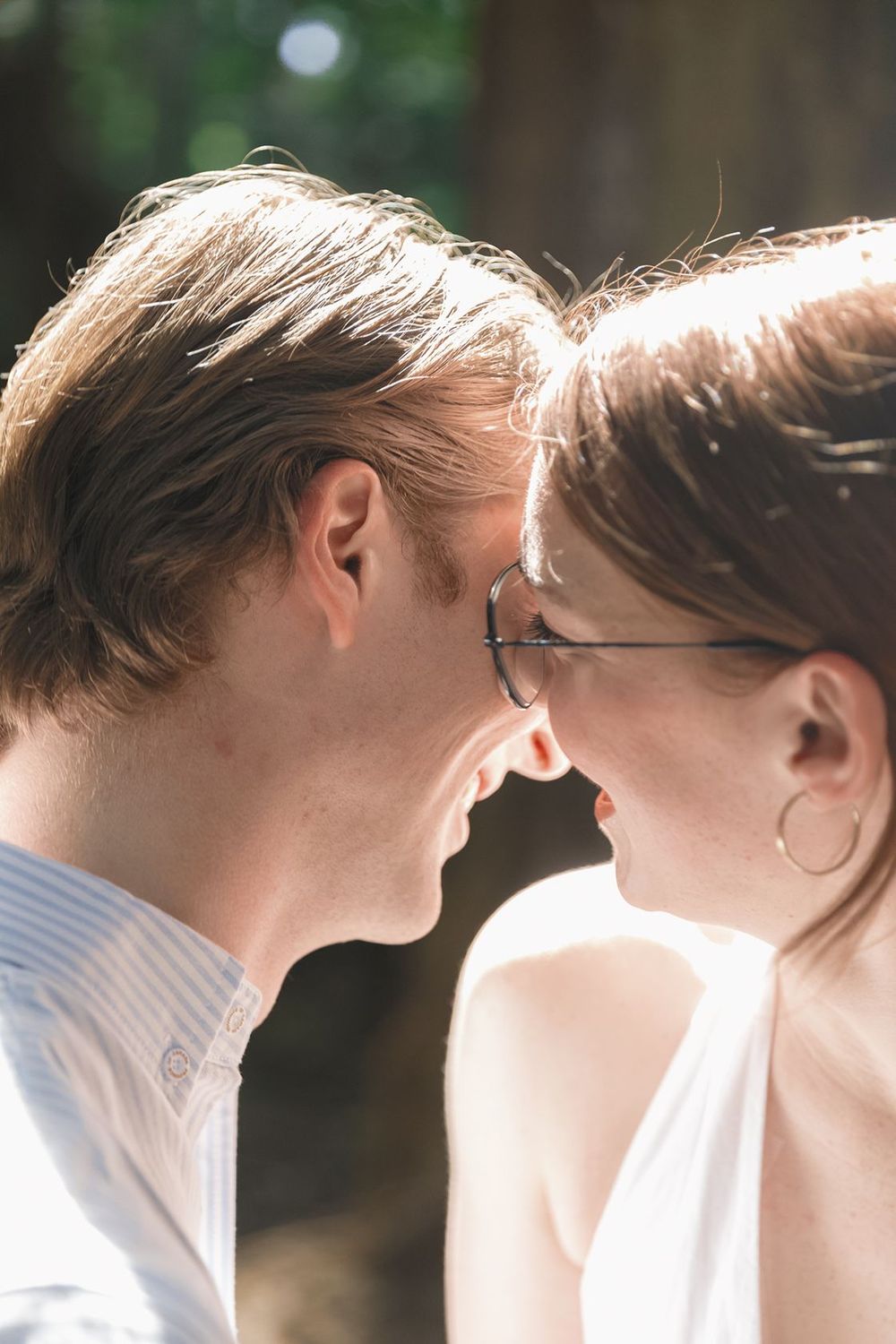 Close-up of a young couple touching foreheads and smiling in a romantic outdoor moment.