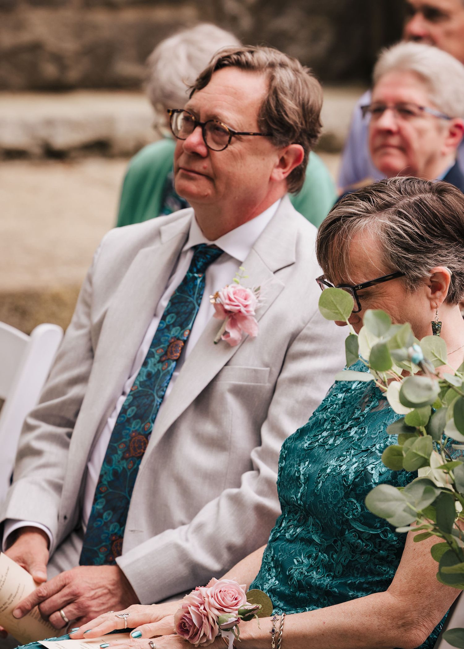 Groom's parents watching the ceremony together, seated among eucalyptus greenery at Searles Castle.