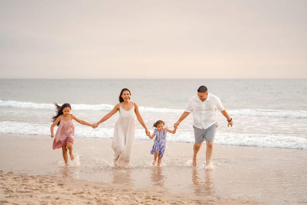 Famille heureuse en train de courir sur la plage au coucher de soleil