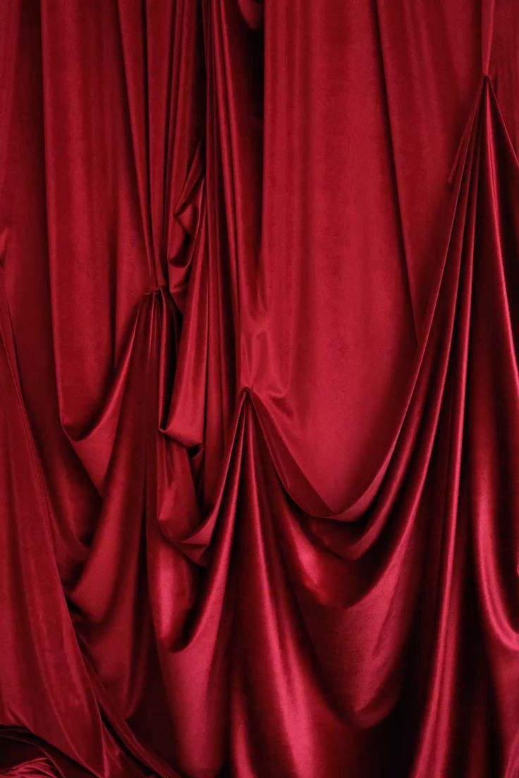 A draped luxurious red velvet curtains.