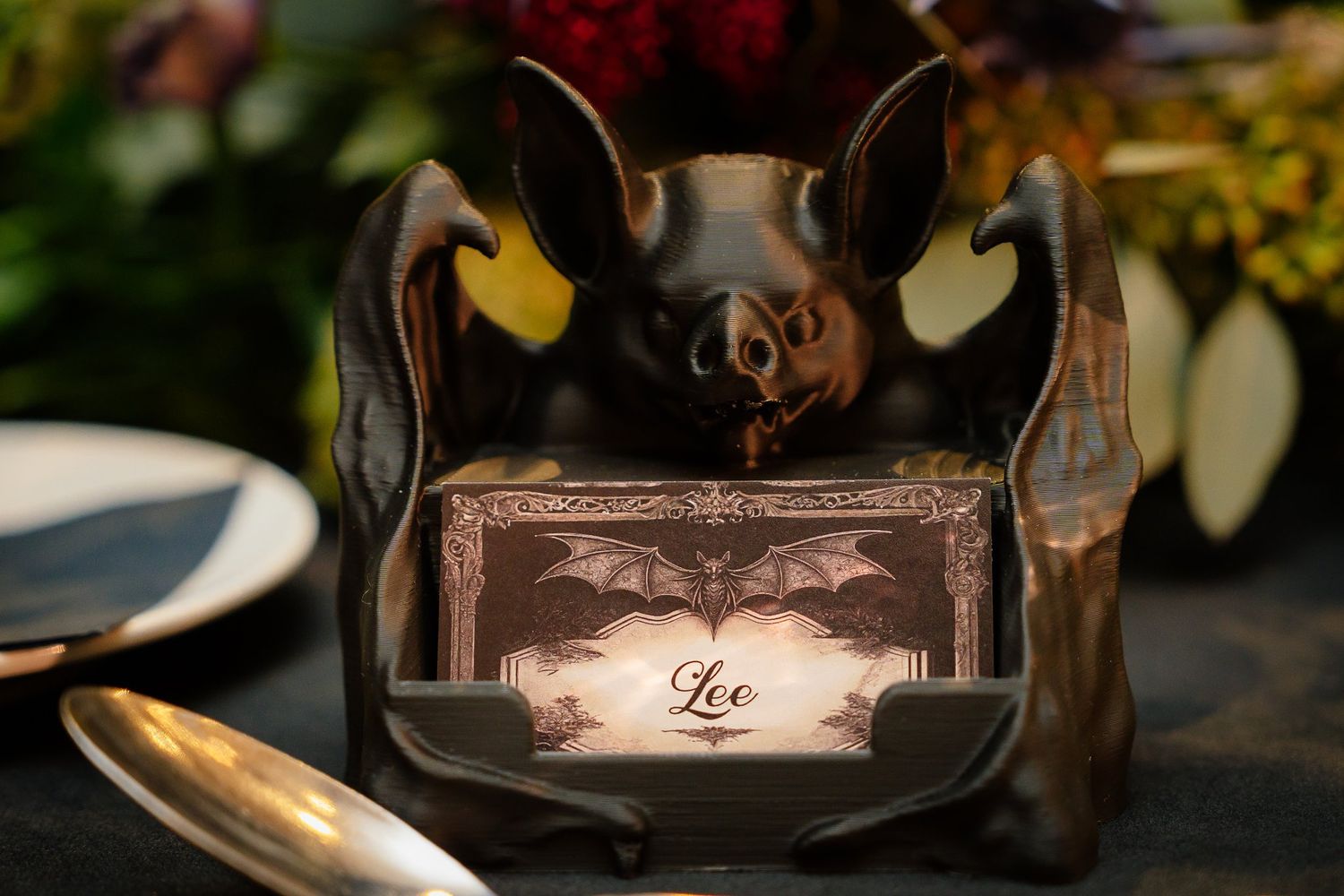 Black bat place card holder with a gothic name card on a Halloween wedding table