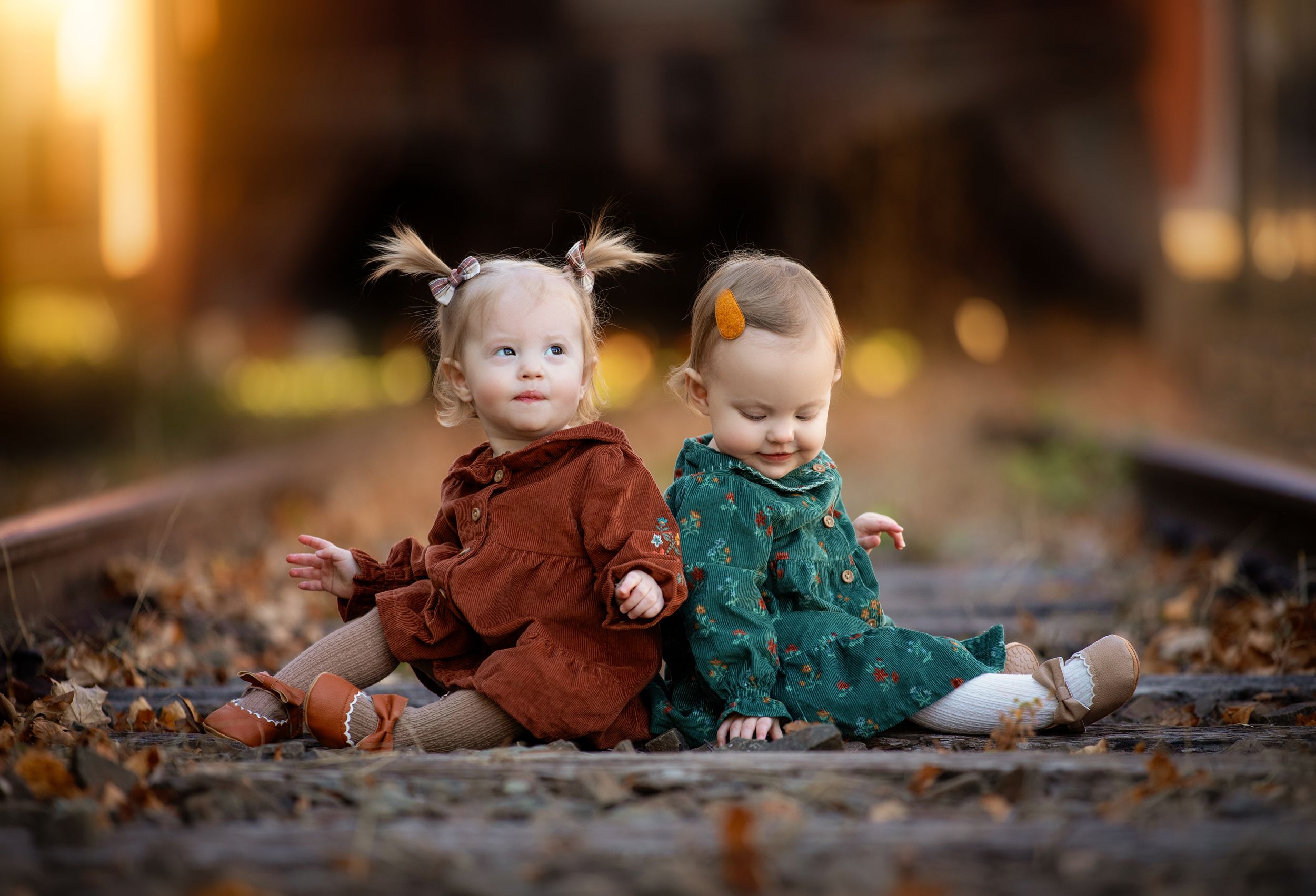 Children playing in autumn leaves on the ground during a fall photo session.
