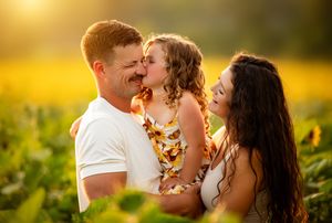 A couple embraces lovingly in a vibrant sunflower field during golden hour sunset.