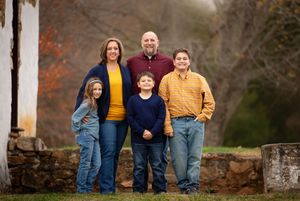 A family in coordinating denim and autumn colors poses together outdoors during fall season.