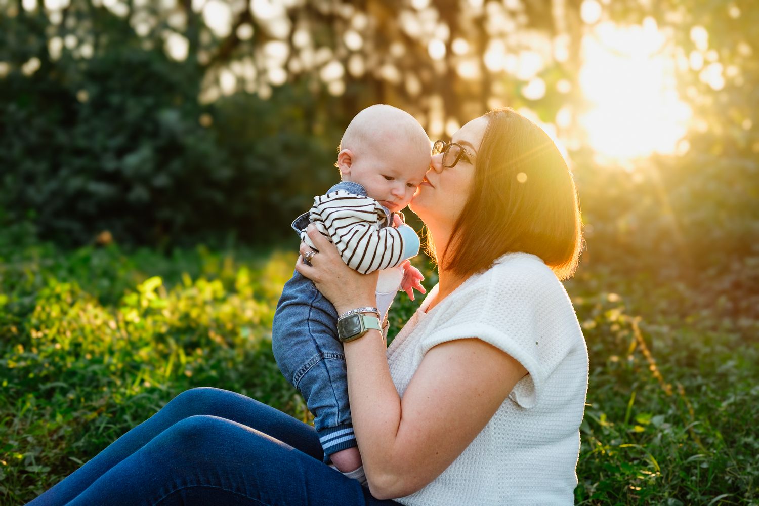 Backlit mother kissing her six-month-old baby boy