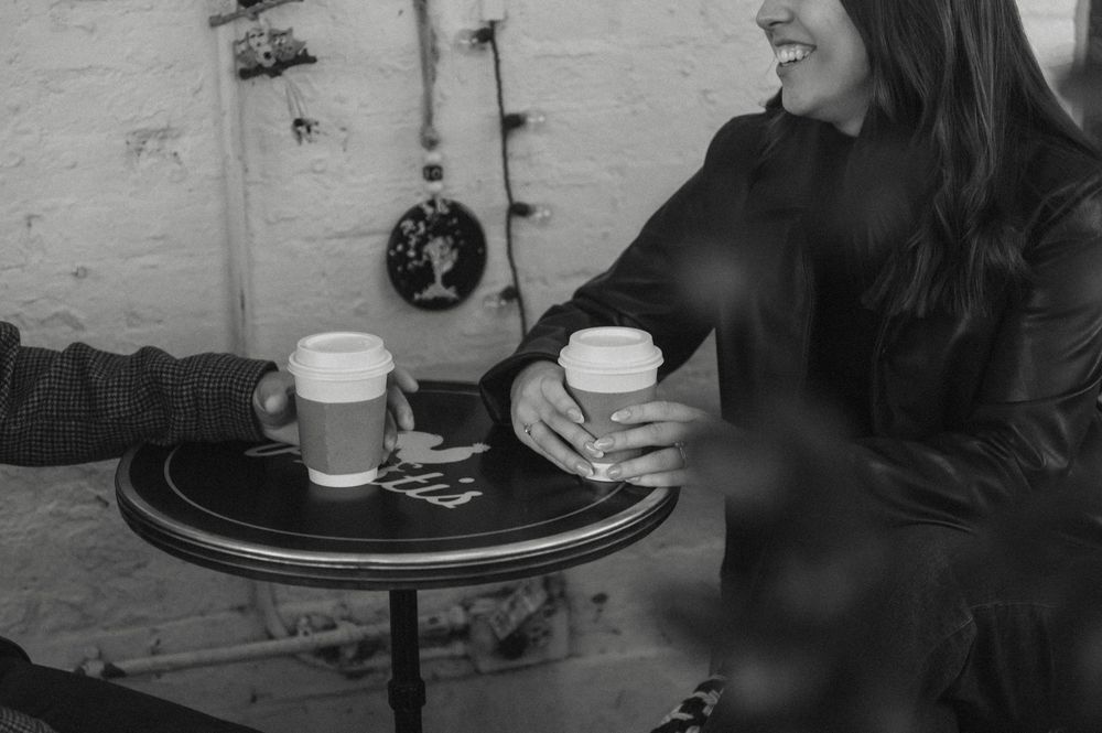 Black and white photo showing people socializing at a casual gathering with drinks and conversation.
