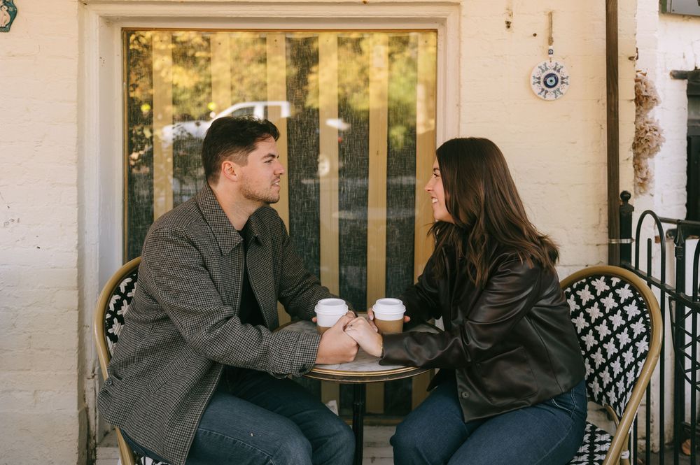 A couple shares coffee at an outdoor cafe table on a sunny afternoon.