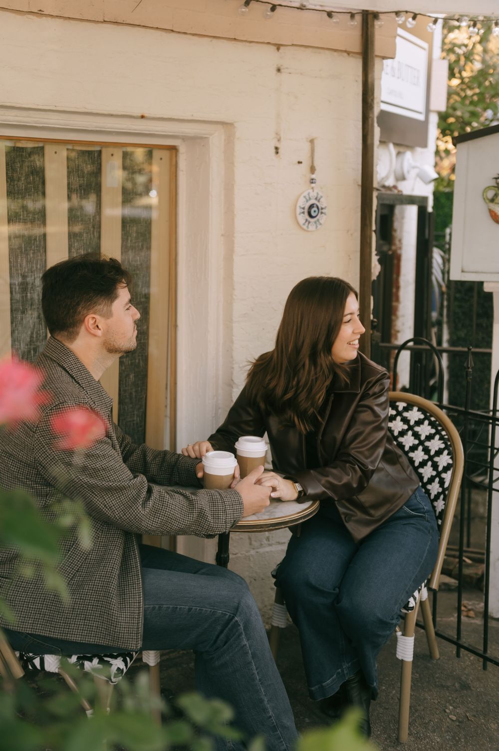A couple enjoys coffee together on a cozy outdoor patio with string lights.