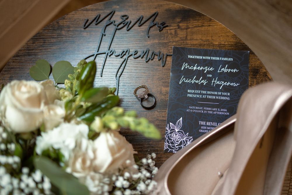 Wedding invitations and paper goods displayed on a reflective surface with white floral decorations.