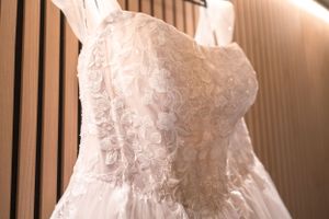 Close-up details of delicate white lace wedding dress with intricate beading and patterns.