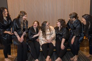 Wedding party members in black attire seated in a row during celebration event.