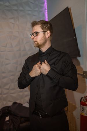 Guest in black attire dancing energetically at indoor wedding reception.