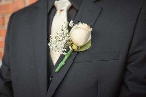 Classic white rose boutonniere pinned to black suit lapel.
