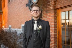 Wedding portrait against brick building with warm sunset lighting.