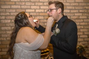 Playful moment of cake feeding during wedding reception.