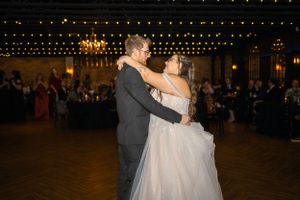 A couple shares their first dance at an evening wedding reception under string lights.