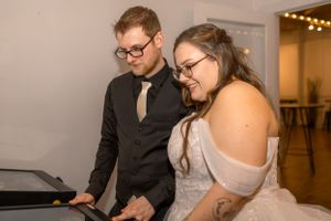 A couple looks down while playing music at an event.