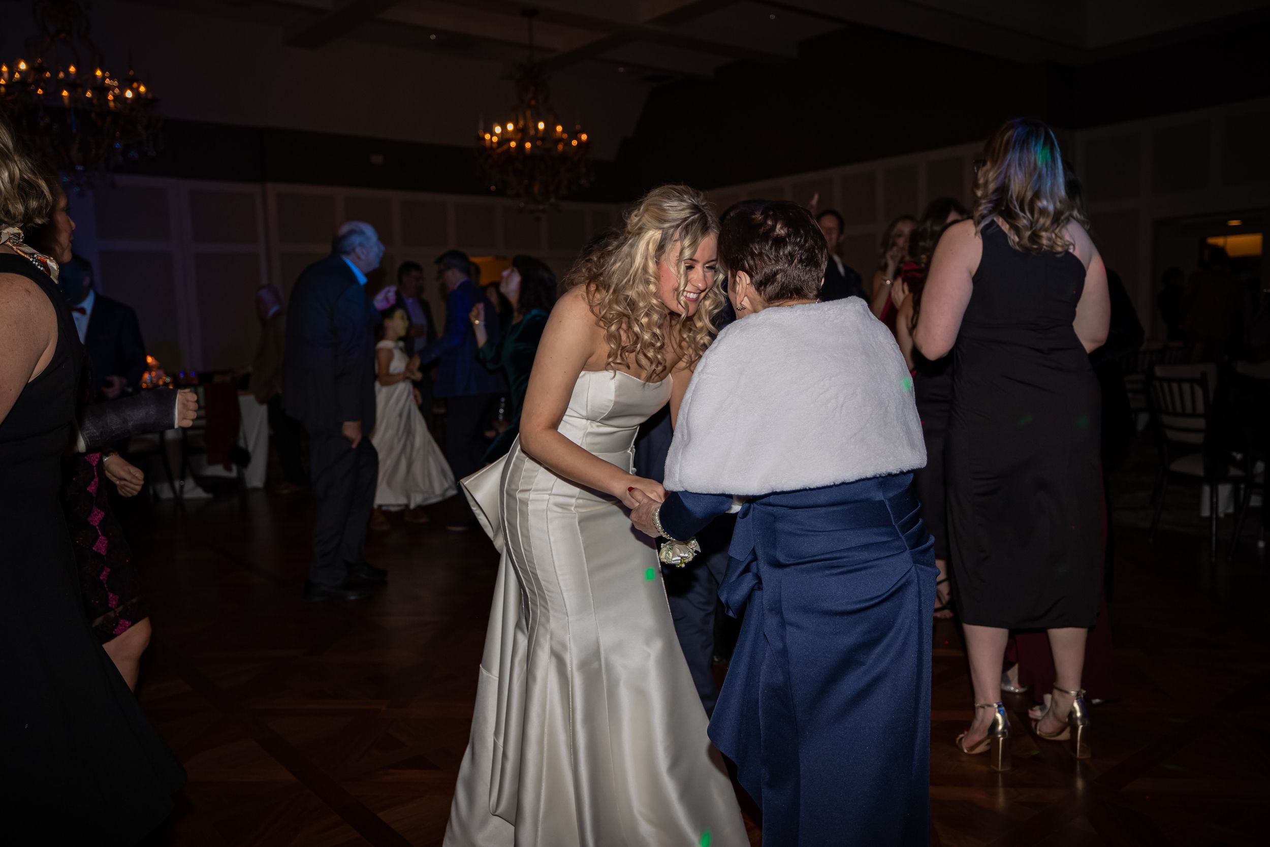 Wedding dancers enjoy themselves under twinkling lights at an evening reception.