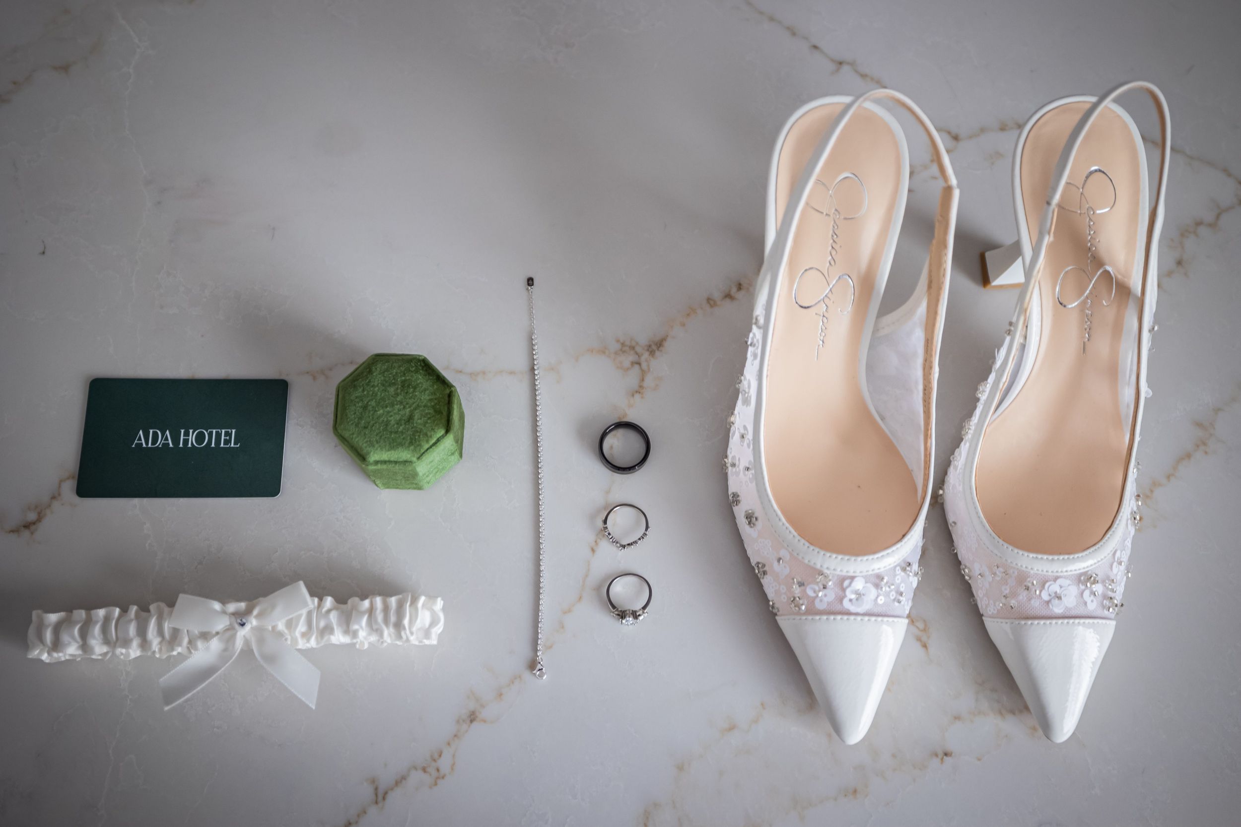 White bridal shoes with delicate embellishments arranged in a row against a marble background.
