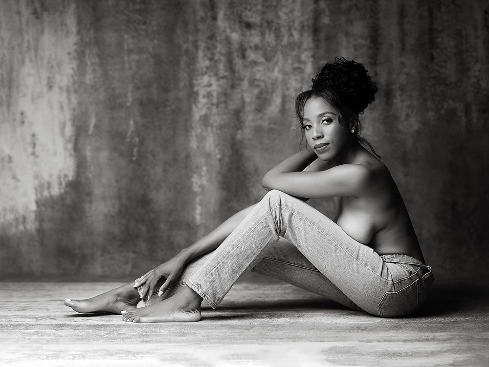 Black and white artistic portrait study showing a graceful reclining silhouette against textured wall.
