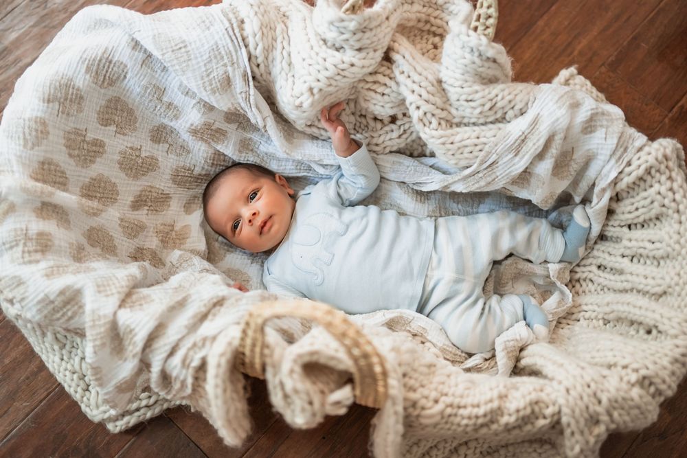 Newborn baby boy nestled in a bassinet for lifestyle newborn photos in home.