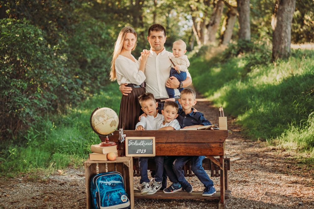 A family poses around a rustic desk in a wooded setting for a back-to-school themed photoshoot.