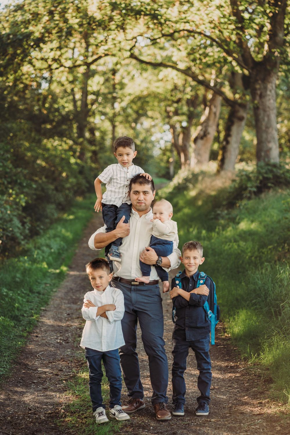 Family portrait on a wooded trail with four children and adult on a sunny afternoon.