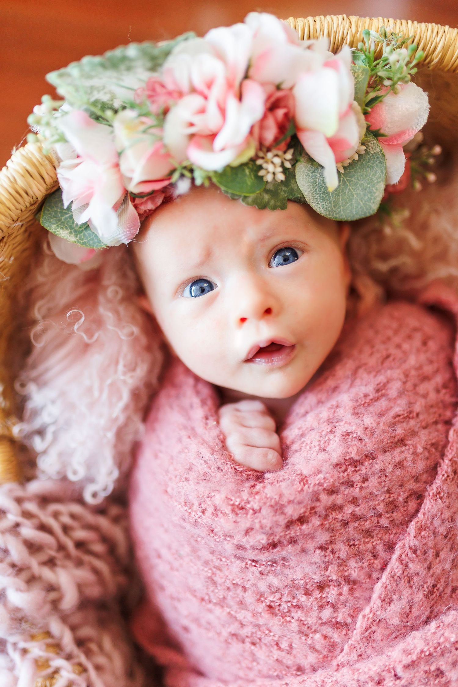 Sleeping newborn wearing mint green outfit on white fur blanket.