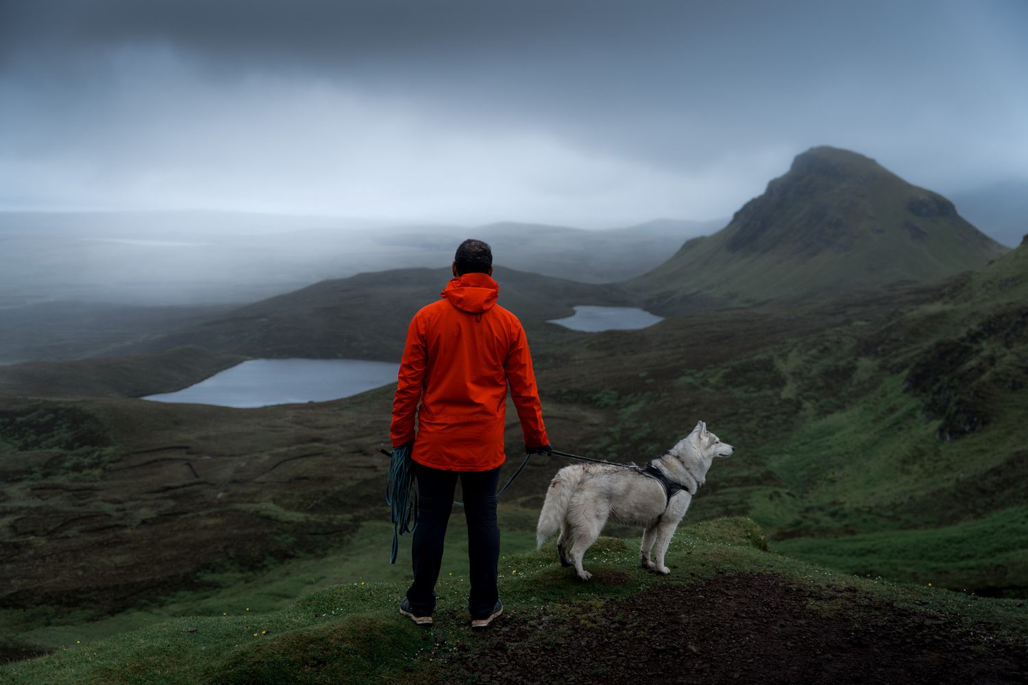 randonneur et son chien devant les lacs de the quiraing sur l'île de skye en ecosse