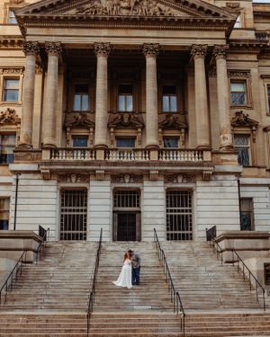 Romantic wedding portrait on the steps of a historic government building with classical columns.