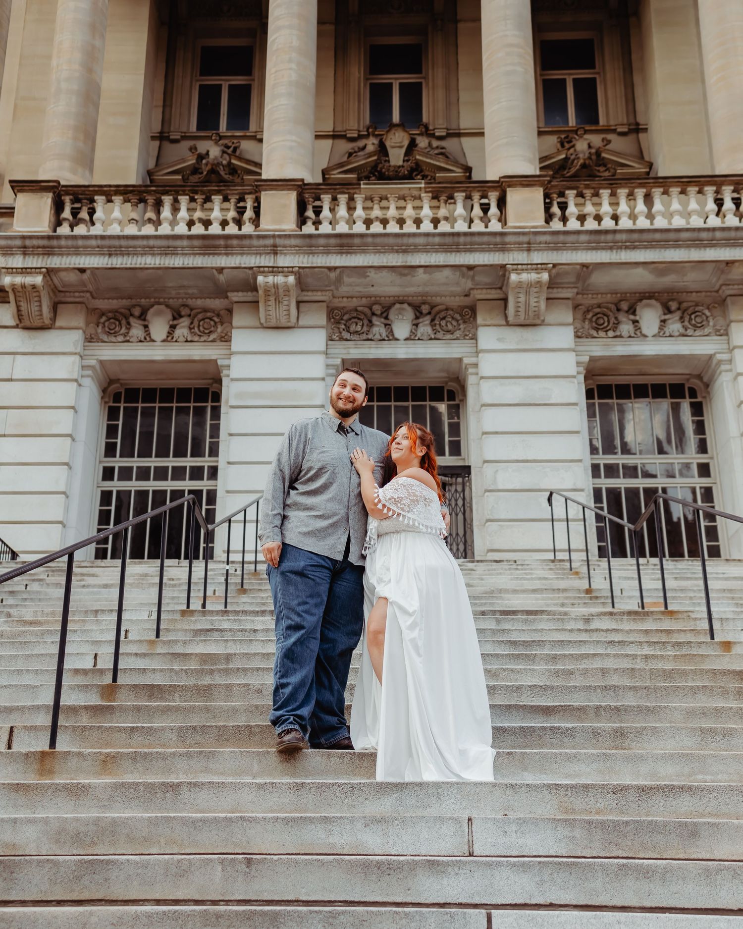 Wedding portrait on stone steps featuring couple against ornate building facade.