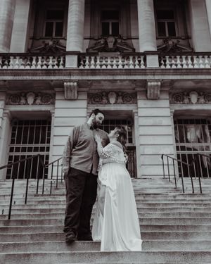 Black and white wedding photo showing couple in embrace on architectural stone steps.