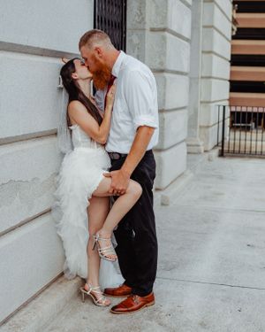 Passionate wedding photo with couple sharing intimate moment against stone wall.