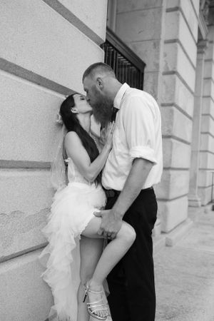Black and white intimate wedding portrait against stone building wall.