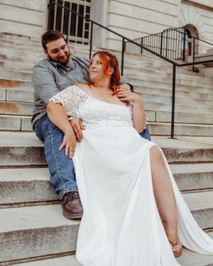 Wedding couple sharing intimate moment on stone building steps.