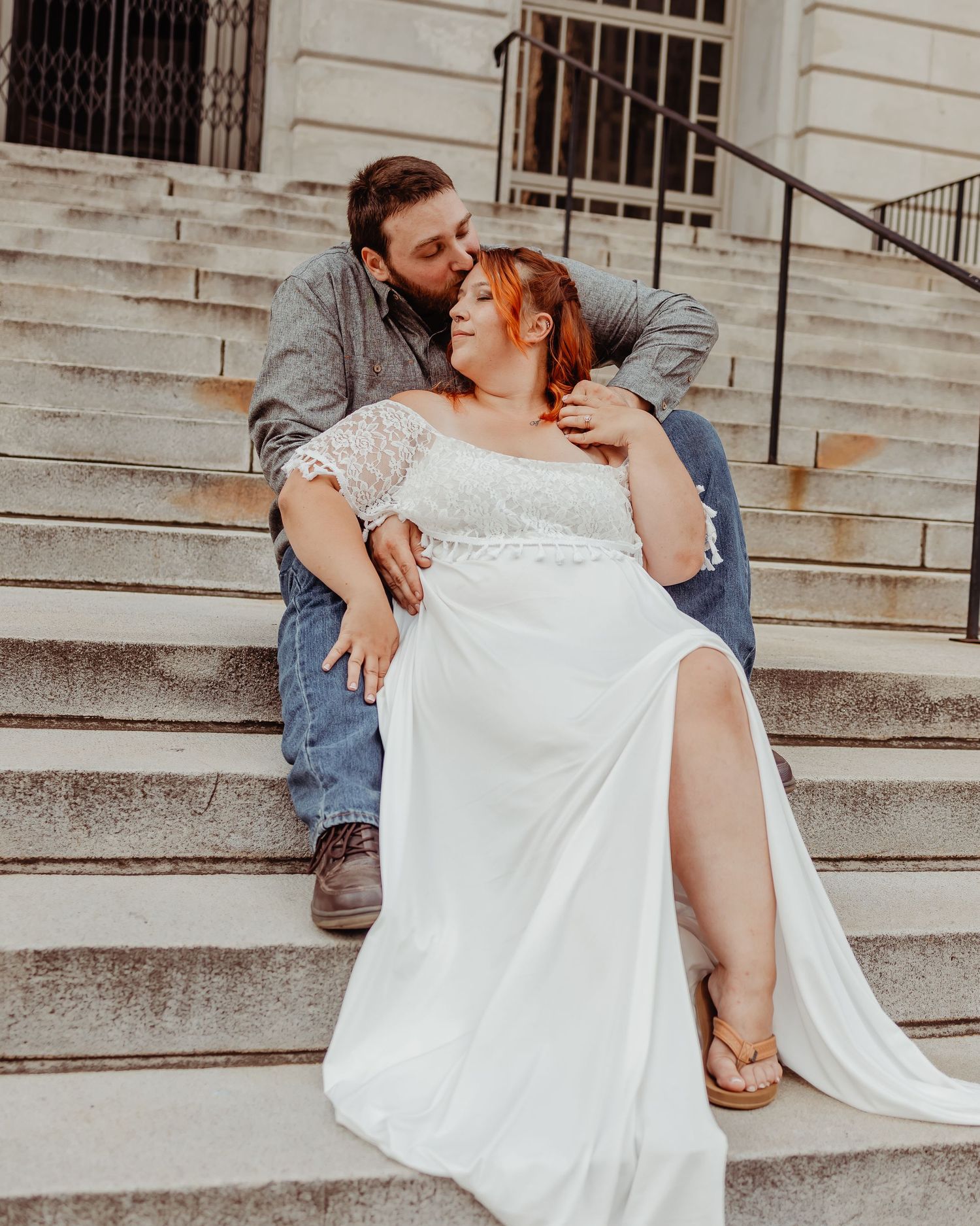 A tender moment captured between newlyweds relaxing on grand stone steps.