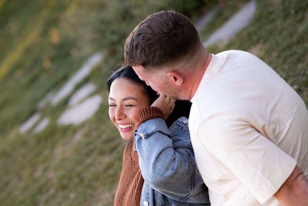 A couple sharing an intimate moment outdoors in casual attire.