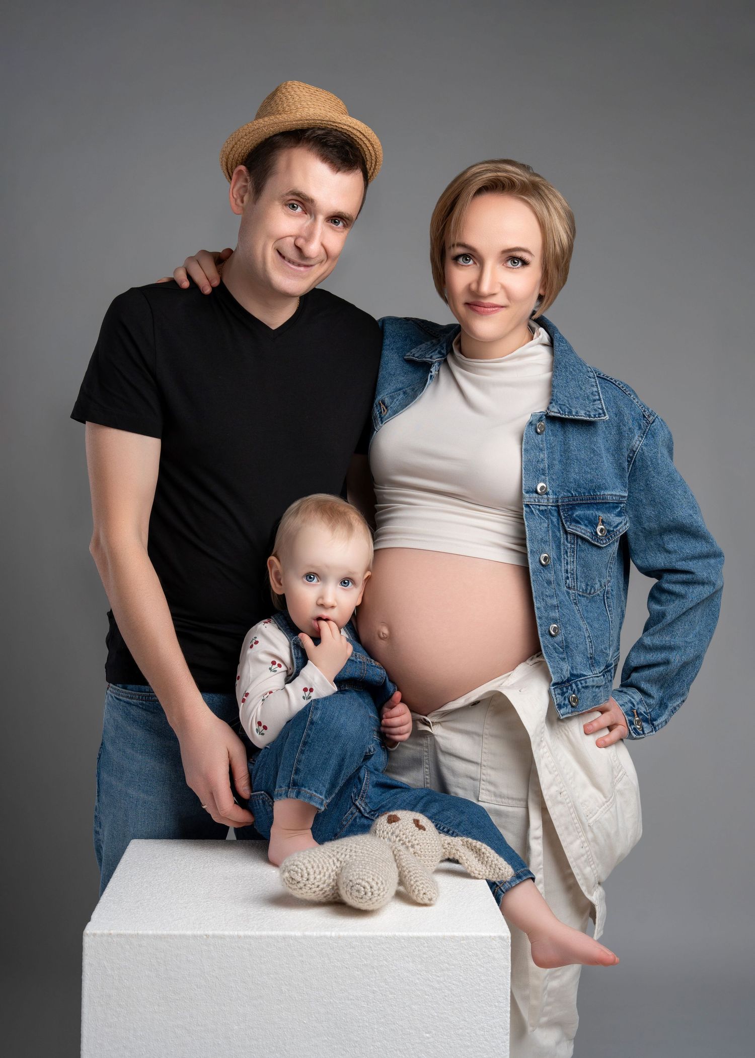 a family of three (and a half) stand together in studio