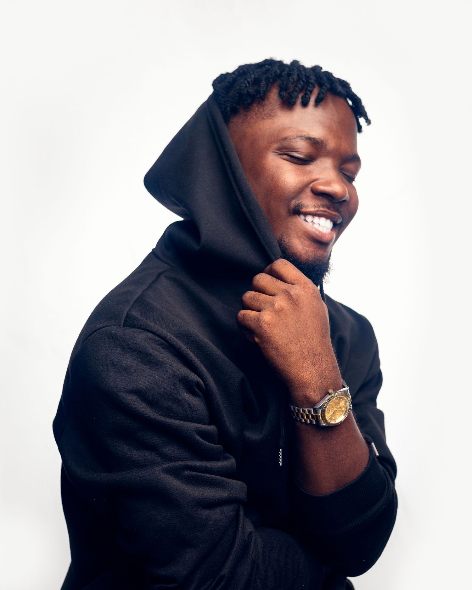 A casual portrait of someone in a black hoodie smiling with eyes closed.