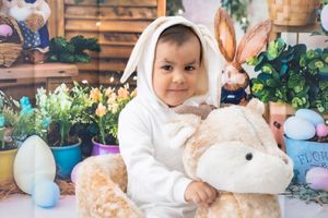 Easter themed baby photo with bunny ears, pastel eggs and spring decorations.